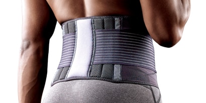 Faja lumbar gris colocada en la parte baja de la espalda de una persona, con bandas elásticas de ajuste y soporte reforzado.
